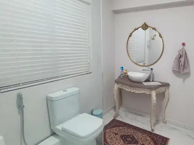 a bathroom with a toilet and a sink and a mirror at Bloubergstrand Beachfront Apartment Witsand 101 in Cape Town