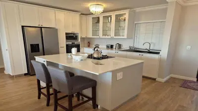 a kitchen with a large island in the middle of a room at Bloubergstrand Beachfront Apartment Witsand 101 in Cape Town