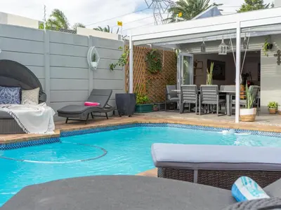 a swimming pool with a table and chairs next to a house at Vida Tranquilo in Edgemead