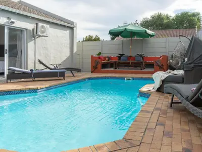 a swimming pool with two chairs and an umbrella at Vida Tranquilo in Edgemead