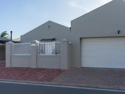 a white house with a gate and a garage at Vida Tranquilo in Edgemead