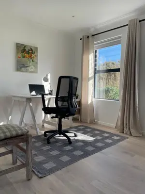 a desk and a chair in a room with a window at Brunia Cottage in Bettyʼs Bay