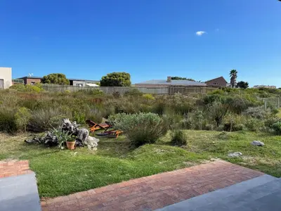 a yard with grass and plants in a field at Brunia Cottage in Bettyʼs Bay