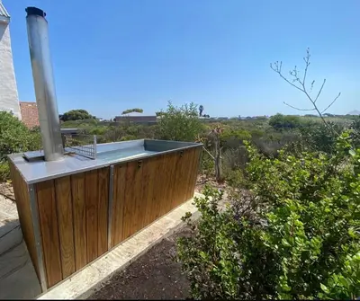 a house with a wooden retaining wall and aestead at Brunia Cottage in Bettyʼs Bay