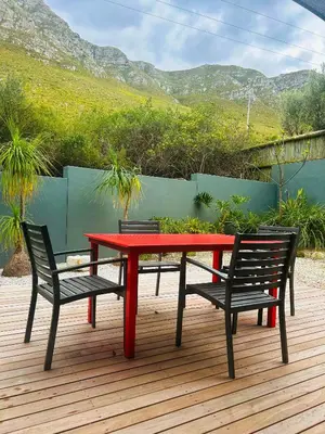 a red table and two chairs on a wooden deck at Villa Silver Vos in Hermanus