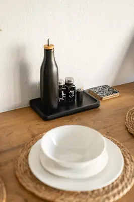 a table with a white plate and a black vase at Ocean Whisper Unit 79 in Hermanus