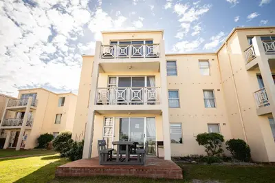 an apartment building with a table in front of it at Ocean Whisper Unit 79 in Hermanus