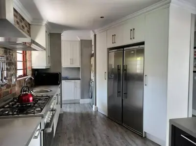 a kitchen with a stainless steel refrigerator and white cabinets at Champers with a view in Cape Town