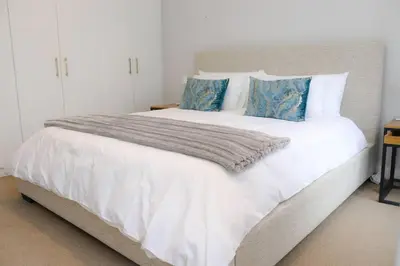 a bedroom with a large white bed with blue pillows at 24 Le Bourgette in Franschhoek
