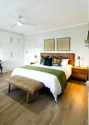 a bedroom with a large bed and a bench at Happy Hideaway in Hermanus