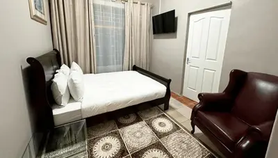 a bedroom with a bed and a chair and a window at Prime Executive Accommodation in Cape Town