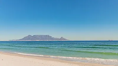 a view of the beach with an island in the distance at Beachfront Luxury Living- A106 Seaspray, Blouberg in Bloubergstrand