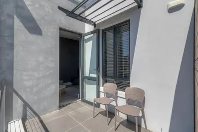a balcony with two chairs and a window at Trebuchet Studio Apartment in Somerset West