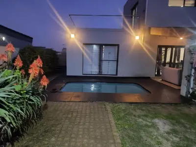 a swimming pool in the backyard of a house at night at Spacious Double Room for Two with Pool, Braai, Gas Stove, Complete Kitchen, Fast WiFi and Private Bathroom in Cape Town