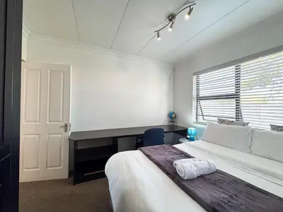 a bedroom with a bed and a desk and a window at Spacious Double Room for Two with Pool, Braai, Gas Stove, Complete Kitchen, Fast WiFi and Private Bathroom in Cape Town