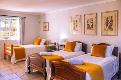 a room with three beds with orange cushions at Seascape, Vermont Retreat in Hermanus
