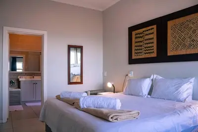 a bedroom with a large bed with white sheets at Seascape, Vermont Retreat in Hermanus