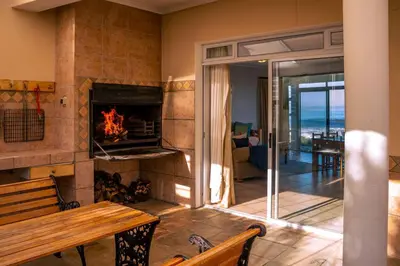 a living room with a fireplace and a wooden table at Seascape, Vermont Retreat in Hermanus