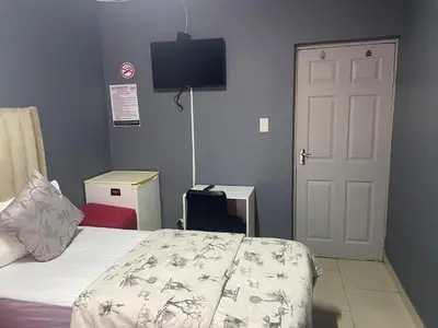 a bedroom with a bed and a tv on the wall at Brooklyn Queens and Kings Guesthouse in Cape Town