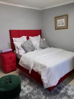 a bedroom with a large bed with a red headboard at Brooklyn Queens and Kings Guesthouse in Cape Town