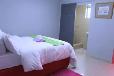 a bedroom with a white bed and a bathroom at Brooklyn Queens and Kings Guesthouse in Cape Town