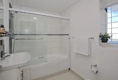 a white bathroom with a shower and a sink at Private Blouberg Beachfront Getaway in Cape Town