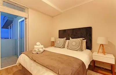 a bedroom with a large bed with a large window at Private Blouberg Beachfront Getaway in Cape Town