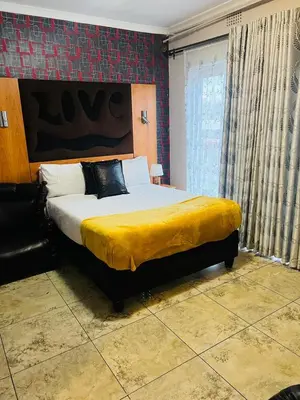 a bedroom with a large bed with a yellow blanket at Parow city -Star Legend Lodge in Cape Town