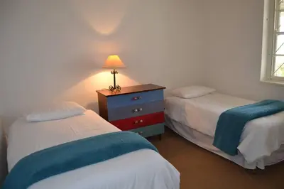 a bedroom with two beds and a dresser with a lamp at Greyt House selfcatering house in Greyton SA in Greyton