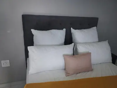 a bed with four pillows on top of it at 160 On Townsend Guesthouse in Cape Town