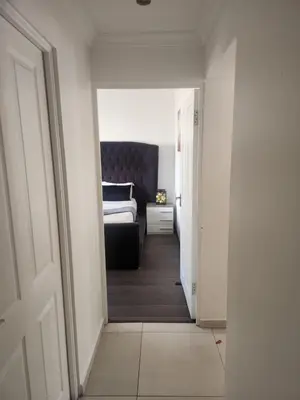 a hallway leading to a bedroom with a bed at Spacious Double Room with Pool, Free WiFi, Self-Catering Kitchen in Cape Town