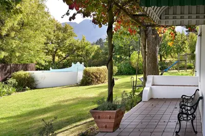 a porch with a bench and a tree in a yard at Bo La Motte Farm Cottages in Franschhoek