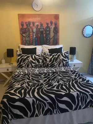 a bedroom with a bed with a painting on the wall at Flaming Place in Cape Town