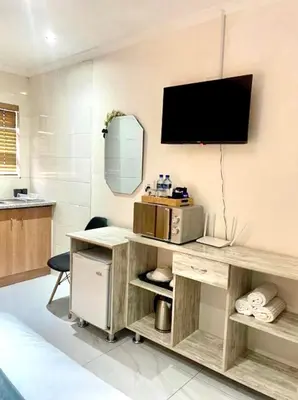 a room with a desk with a television on a wall at Serena Inn Room 3 in Cape Town