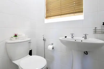 a white bathroom with a toilet and a sink at Serena Inn Room 3 in Cape Town