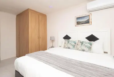 a bedroom with a large white bed and a wooden cabinet at Serena Inn room 2 in Cape Town
