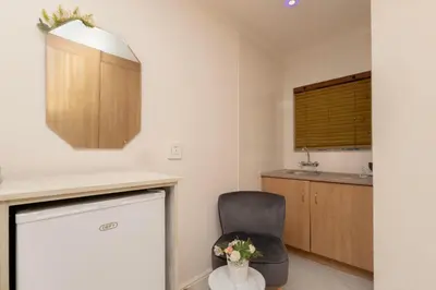 a kitchen with a black chair and a table at Serena Inn room 2 in Cape Town