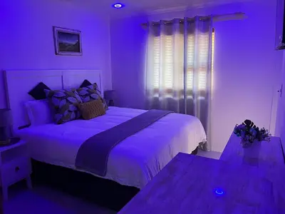 a purple bedroom with a bed and a window at Serena Inn room 2 in Cape Town