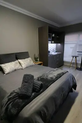 a bedroom with a bed with two towels on it at Charming Modern Bedsitter in Cape Town