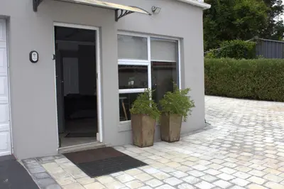 a white house with two potted plants next to it at Charming Modern Bedsitter in Cape Town