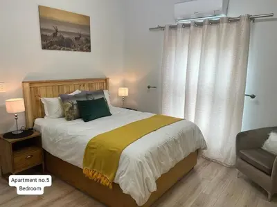 a bedroom with a large bed and a chair at Serena Inn Apartment no5 Self Catering in Cape Town