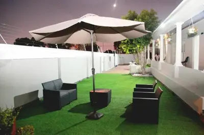 a patio with an umbrella and chairs on the grass at Serena Inn Apartment no5 Self Catering in Cape Town