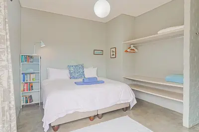 a small bedroom with a bed and a book shelf at Lily House in Bettyʼs Bay