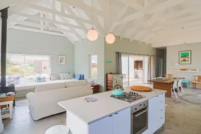 a kitchen and living room with a couch and a table at Lily House in Bettyʼs Bay