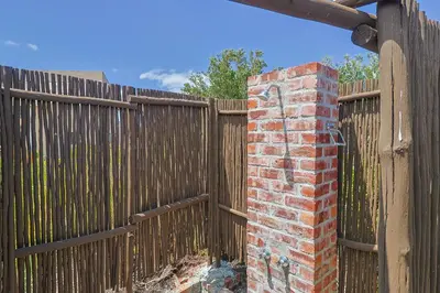 a wooden fence with a brick pillar in front of a gate at Lily House in Bettyʼs Bay