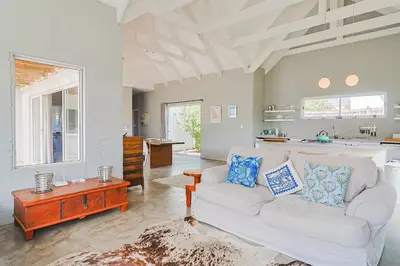 a living room with a couch and a table at Lily House in Bettyʼs Bay
