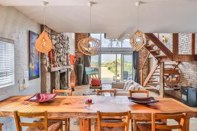 a dining room with a wooden table and chairs at Mountain View in Bettyʼs Bay