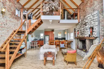 a living room with a staircase and a brick wall at Mountain View in Bettyʼs Bay