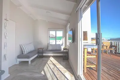 a living room with a couch and a balcony at Beautiful family beach cottage! in Pringle Bay
