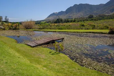 a wooden bridge over a river with mountains in the background at Villetta in Mosselrivier